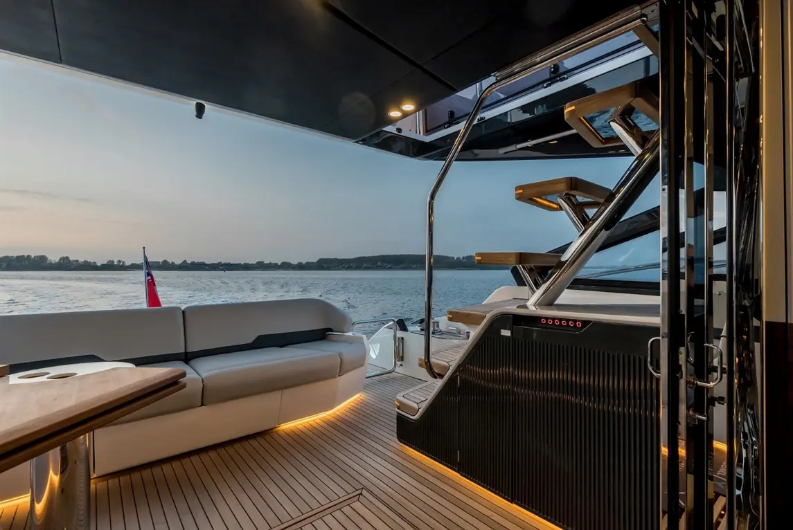 Luxury yacht deck with seating, stairs, and sunset view over water, showcasing modern design and comfortable space.